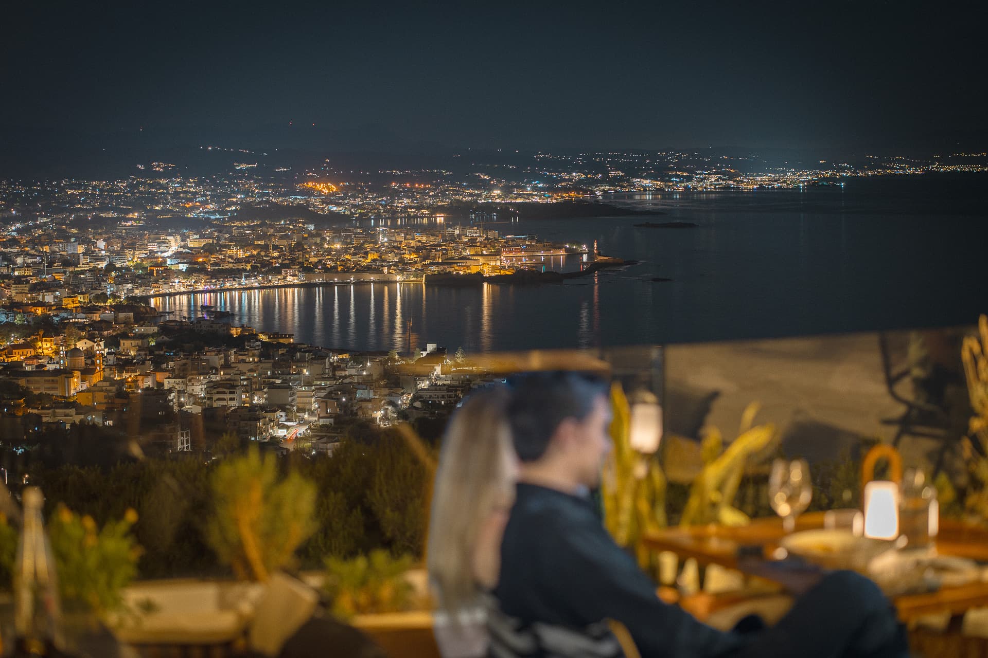 The lights of Chania harbor reflected in the bay at dusk, seen from the terrace of Carte Postale.
